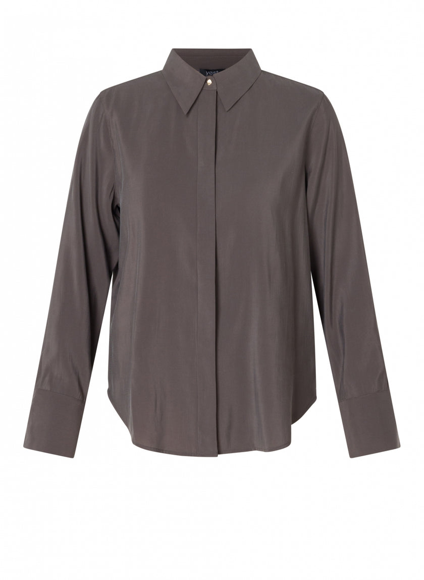 De Clara blouse in chocoladebruin is een knoopmodel met lange mouwen, gemaakt van een zachte viscosemix, met een puntige kraag en brede manchetten, tegen een effen witte achtergrond.