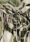 Close-up van de Carmen - Legergroene viscose blouse met een organisch groene en beige print, halslijn met koord, wijde mouwen en een zichtbaar label onder de gerimpelde stof.