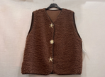 Het Gilet met ster-en zon is een mouwloos, bruin, donzig vest dat aan een zwarte hanger hangt. Het heeft drie stervormige spelden als sluiting aan de voorkant en een subtiel ster- en zonpatroon. De achtergrond is effen en lichtgekleurd.