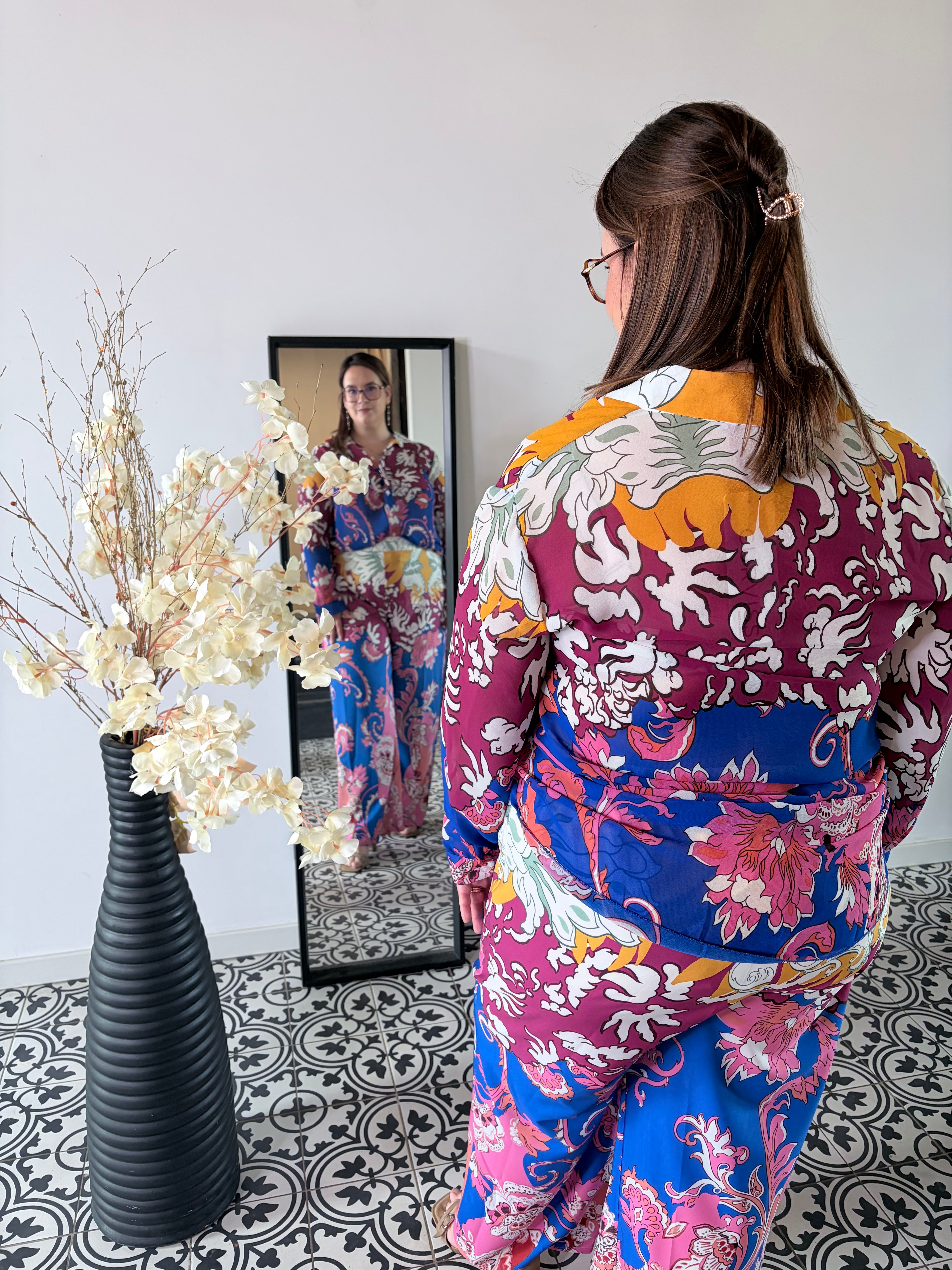 Vrouw draagt een kleurrijke blouse met bloemen en paisley print van Curviss
