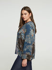 Een vrouw met lang bruin haar draagt de Bohemian blouse - Mat Fashion met wijde mouwen en een donkerblauwe jeans, staand in profiel tegen een effen lichte achtergrond - een ideale boho stijl.