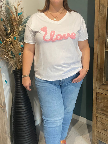 Een vrouw met lichtbruin haar draagt het witte T-shirt - love, met 