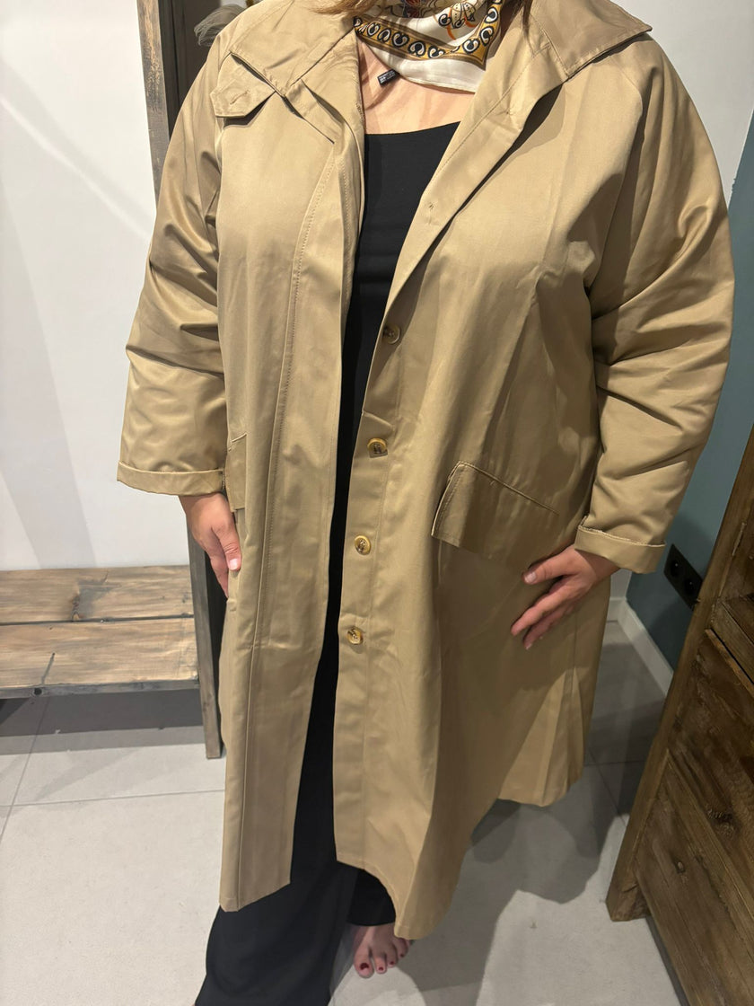 Een persoon modelleert de Trenchcoat - Zwart - Blauw - Bruin over een zwarte outfit en sjaal met patroon binnenshuis, één hand in de zak, gezicht niet zichtbaar.